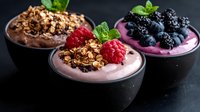 Healthy berry smoothie bowls with granola, fresh raspberries, blackberries and mint leaves. Nutritious breakfast or snack option for wellness lifestyle.