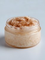 Homemade cinnamon sugar body scrub in glass jar against neutral background, natural skincare product for exfoliation and skin care routine.
