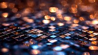 Computer keyboard illuminated with blue backlight and orange bokeh effects creating atmospheric technology background with shallow depth of field.