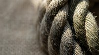 Coiled natural rope with frayed texture and rustic hemp fibers creating nautical maritime background for vintage design projects.