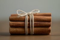 Bundle of cinnamon sticks tied with natural twine rope on wooden surface. Aromatic spice ingredient for cooking, baking and holiday recipes.