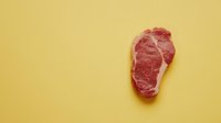 Raw marbled beef steak on yellow background with copy space. Fresh premium cut meat for restaurant menu, cooking, or food photography.