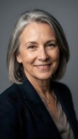 Mature woman with gray hair and warm smile wearing dark blazer against neutral background, suitable for corporate and professional use.