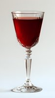 Crystal wine glass filled with deep red wine against light background, showcasing elegant cut glass pattern and tall stem design for luxury dining and events.