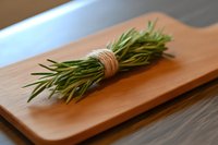 Fresh rosemary sprigs tied with twine on wooden cutting board, macro food photography with soft natural lighting and shallow depth of field.