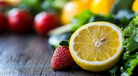 Fresh ripe strawberry next to sliced yellow lemon half with vibrant fruits and green leaves on rustic wooden background, macro food photography.