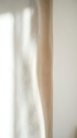 Soft natural light streaming across neutral beige textured wall and fabric surface, creating subtle shadows and highlights for minimalist interior design and home decor projects.