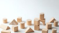 Natural wooden geometric shapes and building blocks scattered on white background for educational toys and creative play activities.