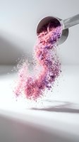 Metallic measuring spoon pouring shimmering pink and purple powder in mid-air against white background, suitable for cosmetics, beauty products, makeup tutorials, and wellness content.