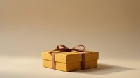 Gold gift box with brown ribbon bow on neutral beige background, isolated for holiday, celebration, and special occasion design projects.