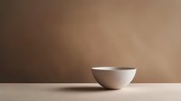 Minimalist white ceramic bowl on beige surface against brown gradient background, creating clean composition with soft shadows and elegant simplicity.