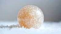Frozen sphere with crystalline ice coating surrounded by snow and frost on neutral background.