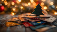 Credit cards scattered with decorative green Christmas tree on top against blurred warm bokeh lights background, representing holiday shopping and financial planning.