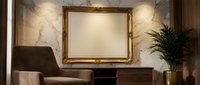 Elegant living room interior with ornate golden picture frame on marble wall, brown leather armchair and potted plant for luxury home decor.