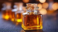 Glass bottle with golden liquid on dark wooden surface against blurred warm bokeh lights background, luxury aromatherapy and spa concept.