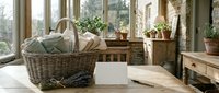 Cozy laundry room interior with wicker basket, wooden furniture and potted plants by large windows creating warm natural lighting for home organization.