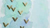 Wooden chevron arrows scattered on soft watercolor paper background in mint green and blue tones for creative projects and design layouts.