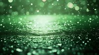 Magical green glowing bokeh background with sparkles and light particles floating in dark space, creating dreamy atmospheric effect. Blurred festive surface.