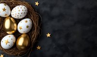 Golden and white Easter eggs decorated with stars in natural nest on dark background with scattered star confetti and copy space for seasonal design.