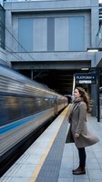 Young woman waiting for express train at modern subway station platform with motion blur effect capturing urban commuter lifestyle and public transportation.