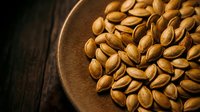 Roasted pistachio nuts in rustic wooden bowl on dark wood surface. Healthy snacking, cooking ingredient for Mediterranean cuisine and gourmet recipes.