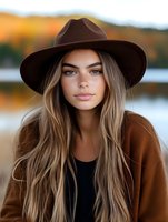 Young woman in brown fedora hat and coat with long blonde hair against autumn lake background, natural makeup look for fashion and lifestyle content.