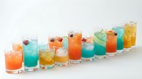Colorful cocktails and mocktails in glasses with ice, garnished with fruits and herbs, arranged in row on white background for party drinks menu.