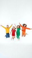Four happy children jumping with arms raised wearing bright colorful clothes on white background isolated for design projects.