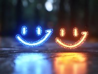 Glowing neon smile faces in blue and orange colors with sparkle effect reflected on wet surface against dark background, creating magical atmosphere.