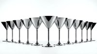 Row of elegant silver metallic martini cocktail glasses arranged in line on white background for party celebration and bar service.