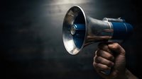 Hand holding vintage metal megaphone with blue accents against dark background with dramatic lighting for communication and announcement concepts.