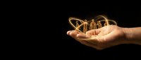 Hand holding glowing light bulb with filament against dark background symbolizing innovation, creativity and bright ideas for business concepts.
