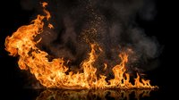 Dramatic orange flames with flying sparks and smoke against black background for fire safety, energy concepts and industrial applications.