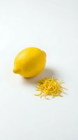 Fresh yellow lemon with zested peel strips isolated on white background for culinary cooking and baking recipes.