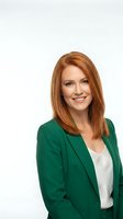 Professional redhead businesswoman in green blazer smiling confidently on white background isolated for corporate design and marketing materials.