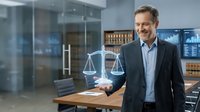 Confident middle-aged Caucasian male lawyer holding scales of justice in modern law office with legal books background for corporate presentations.