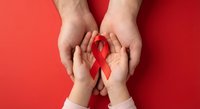 Adult and child hands holding red ribbon on red background symbolizing HIV AIDS awareness, healthcare support, medical advocacy and community solidarity.