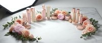 Elegant rose gold cosmetic bottles arranged in circle with pink roses and eucalyptus on marble surface for luxury beauty brand mockup and product display.