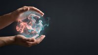Hands holding glowing energy orb with orange and blue light effects against dark background, representing power, magic, technology, innovation, and digital transformation concepts.