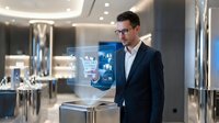 Professional businessman in suit using holographic shopping cart interface in modern retail store environment for digital commerce technology.