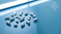 White and blue pharmaceutical capsules scattered on clean medical surface with soft lighting for healthcare and medicine concepts.