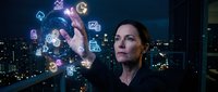 Professional businesswoman interacting with futuristic holographic interface displaying digital icons and data visualization in modern office setting.