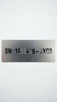 Metal nameplate with serial number engraved on brushed aluminum surface isolated on white background for industrial labeling and identification purposes.