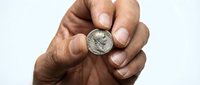 Hand holding vintage silver coin between fingers on white background isolated for numismatic collection design.