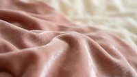 Soft pink fabric with gentle folds and wrinkles creating elegant textile texture for fashion design, home decor and luxury material backgrounds.