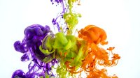Vibrant purple, green and orange ink drops swirling in water creating abstract fluid motion patterns on white background for creative design projects.