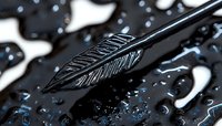 Black metallic arrow-shaped pen nib with intricate engraved pattern captured in macro photography against dark background with water droplets creating dramatic lighting effect.