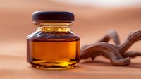 Small glass jar with golden maple syrup or honey on beige background with decorative wooden element, natural food photography for packaging design.