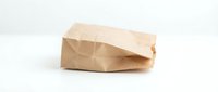 Crumpled brown kraft paper bag on white background, suitable for packaging, food delivery, retail, and eco-friendly commerce designs.