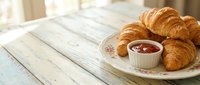 Freshly baked croissants arranged on a plate with jam for breakfast or bakery marketing, food photography for cafes and restaurants.